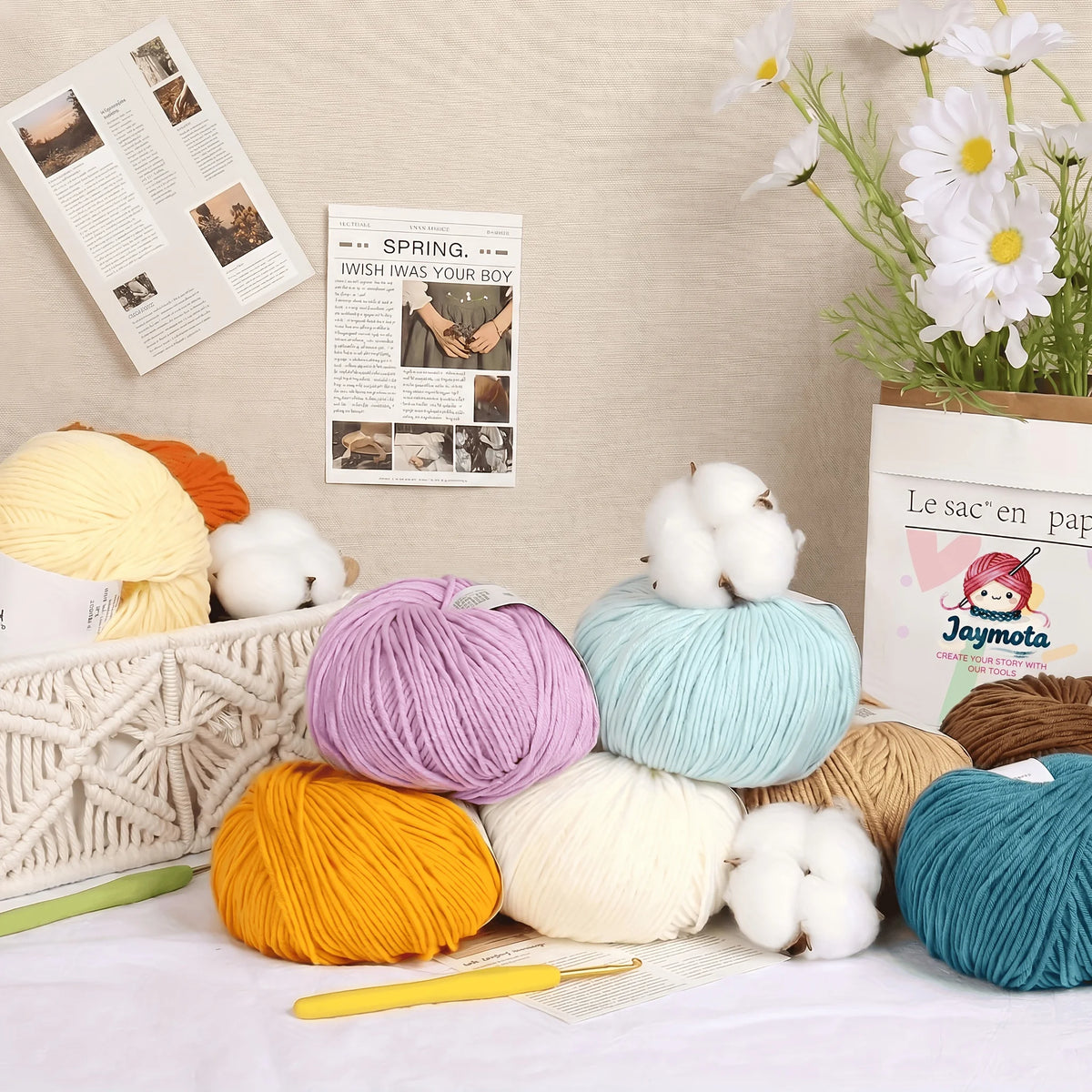 Pelotes de laine pastel posées sur une table à côté d'un crochet et d'animaux tricotés
