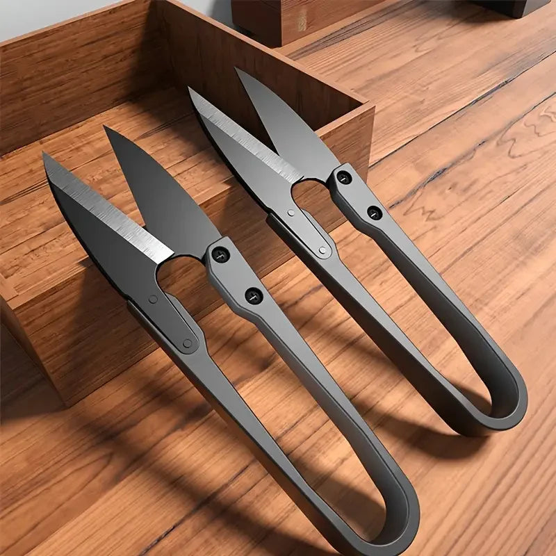 Lot de deux ciseaux coupe-fil de couture noirs en acier posés sur une table en bois