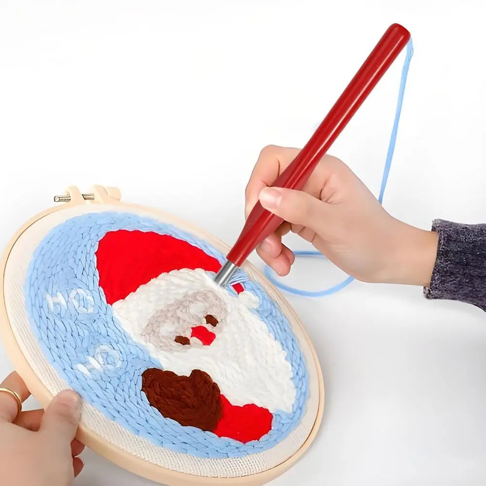 Main utilisant l'aiguille de punch needle rouge pour broder un motif de Père Noël sur un tambour
