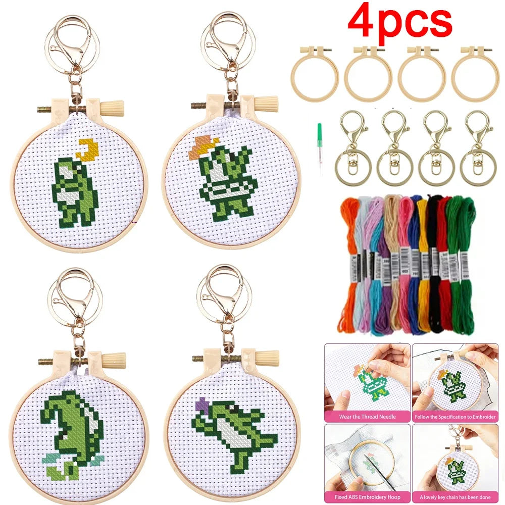 Kit complet de broderie pour debutant avec lot de quatre mini tambours porte-cles motifs de petits dinosaures verts rigolos echeveaux de fils de couleur et mousquetons.