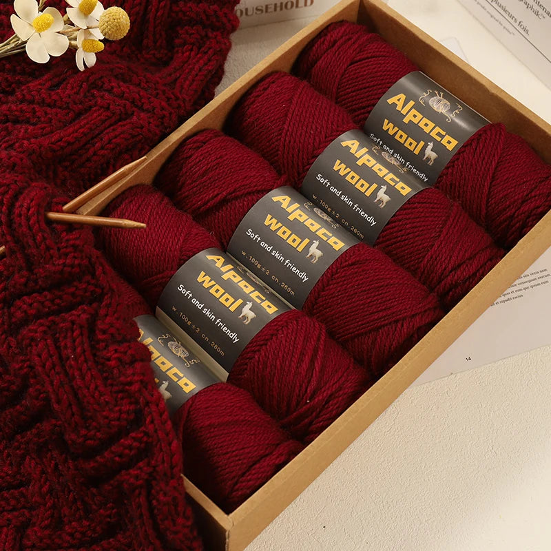 Boîte de présentation contenant cinq pelotes de laine couleur rouge bordeaux brique