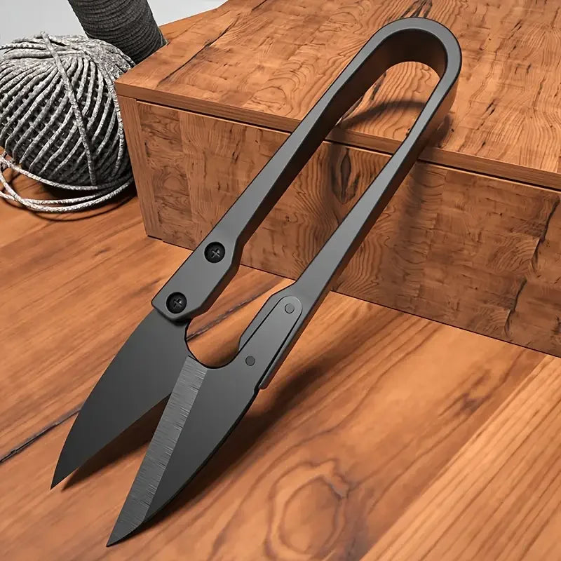 Ciseau coupe-fil noir de tailleur posé à la verticale à côté d'une boîte en bois