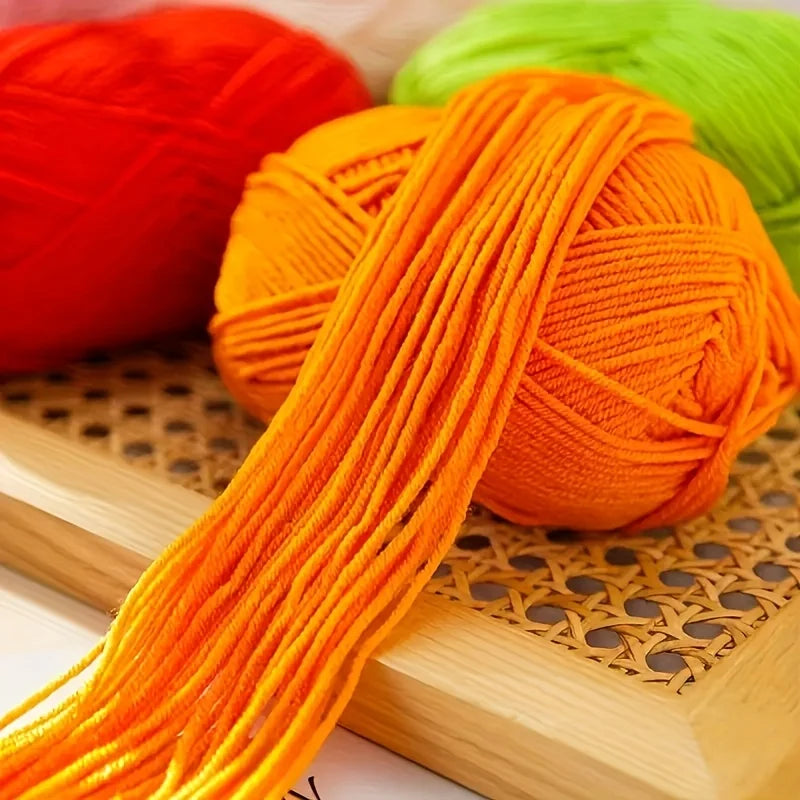 Gros plan sur le fil d'une pelote de laine orange vif posée sur un support en bois dans l'atelier