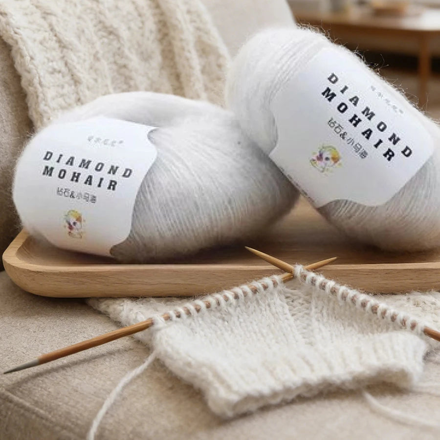 Échantillon de tricot blanc en cours avec des aiguilles en bois et deux pelotes de laine mohair