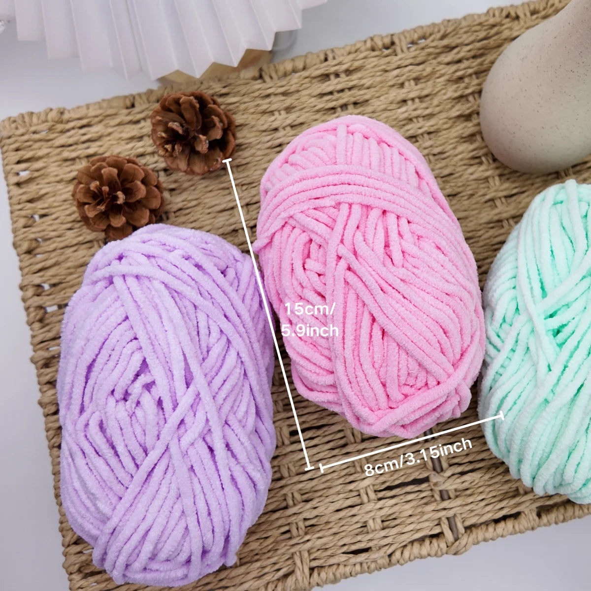 Pelotes de laine chenille pastel jaune violet rose et menthe sur un fond de paille