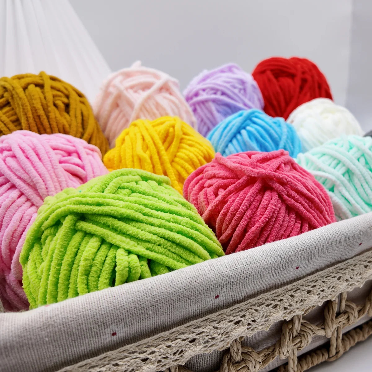Assortiment de pelotes de fil chenille colorées disposées dans un panier de rangement