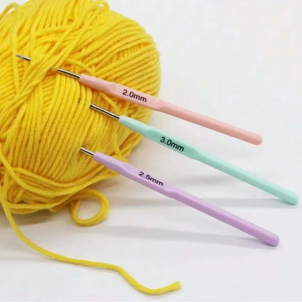 Mise en scène créative avec trois crochets colorés plantés dans une grosse pelote de laine jaune