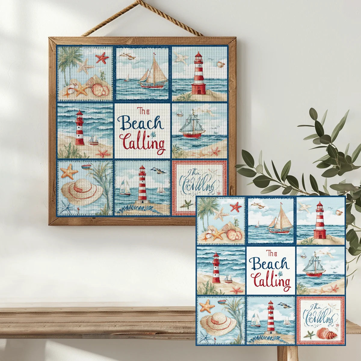 Tableau en broderie point de croix thème marin The Beach is Calling encadré en bois et accroché sur un mur blanc à côté d'une plante.