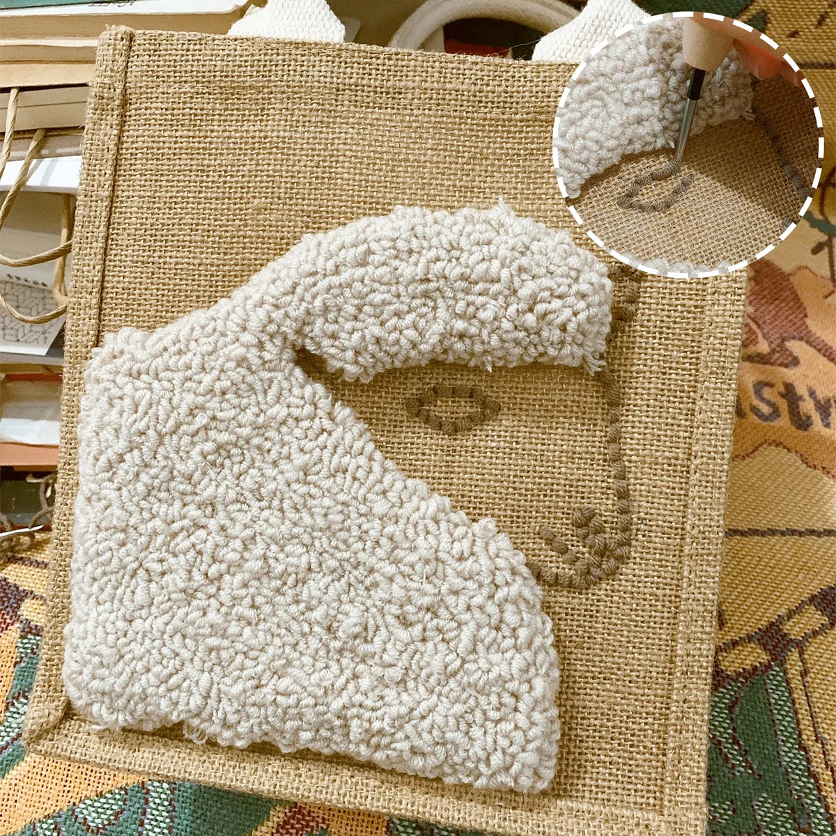 Exemple d'ouvrage textile montrant une broderie punch needle en relief représentant un mouton blanc sur une toile de jute.