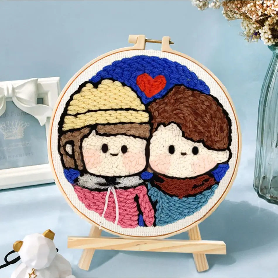 ambour de broderie fini représentant un couple de personnages amoureux au style mignon, exposé sur un mini chevalet en bois.