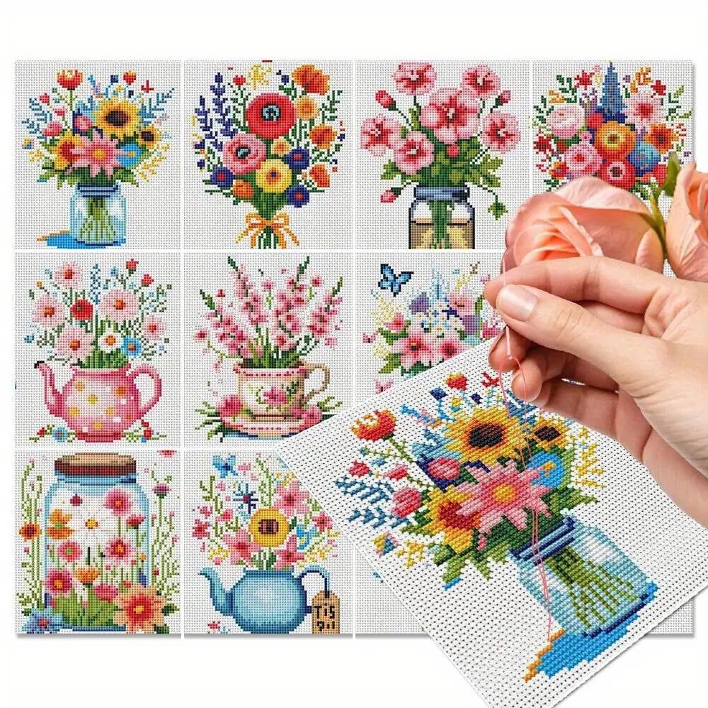 Main tenant une aiguille pour broder un kit de point de croix complet affichant une collection de huit motifs de bouquets de fleurs printanieres pivoines et lavande dans des theieres et des bocaux en verre.