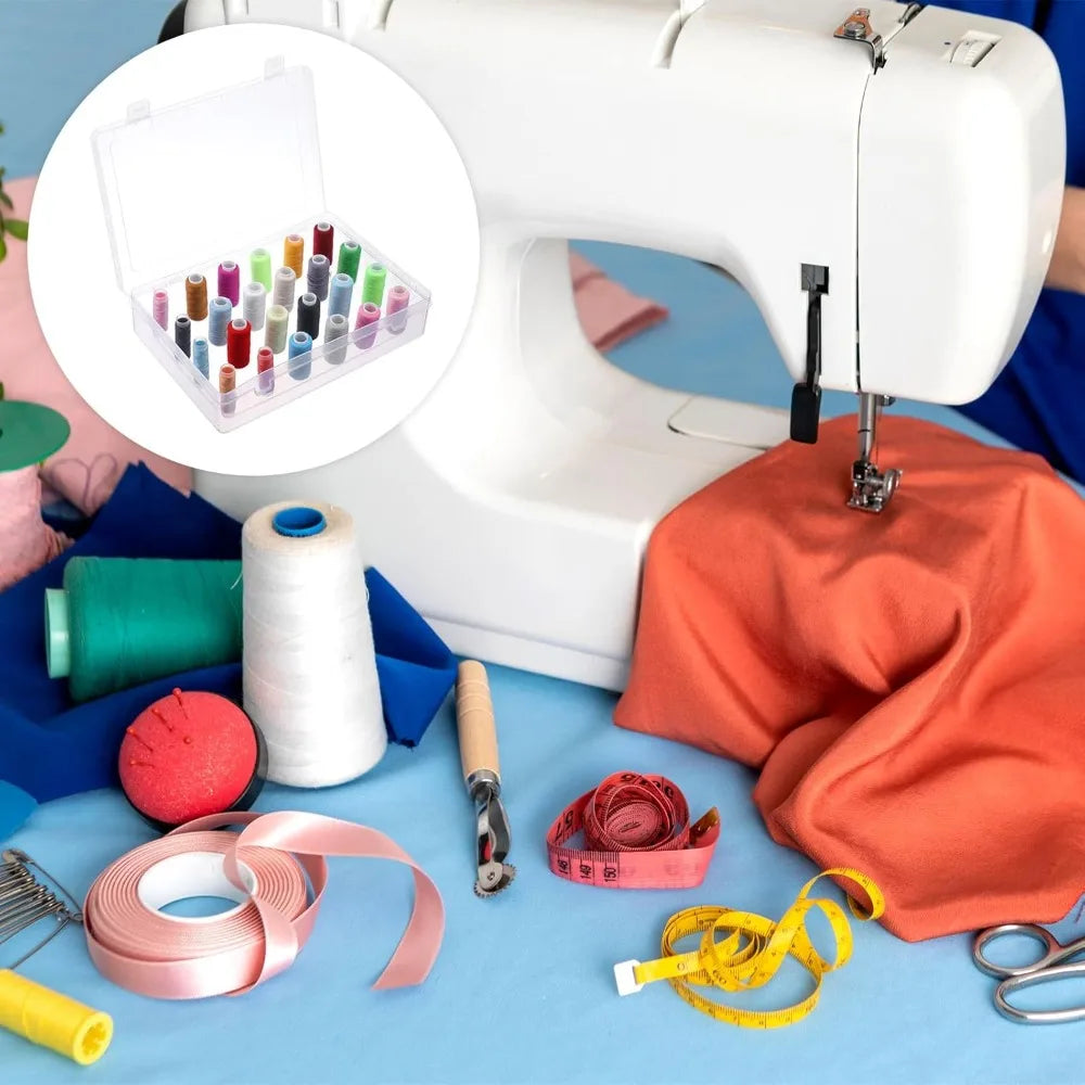 Boite a fil de couture transparente posee sur un plan de travail a cote d'une machine a coudre et de petits accessoires de mercerie.