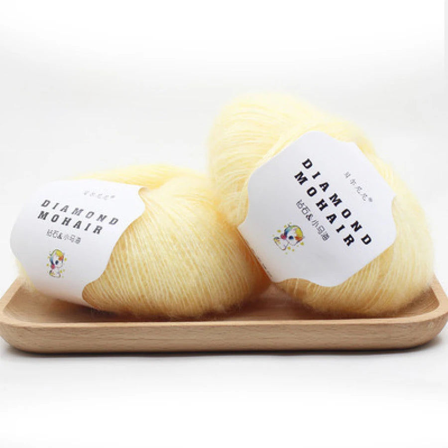 Deux pelotes de laine Diamond Mohair couleur jaune vanille clair sur un support en bois