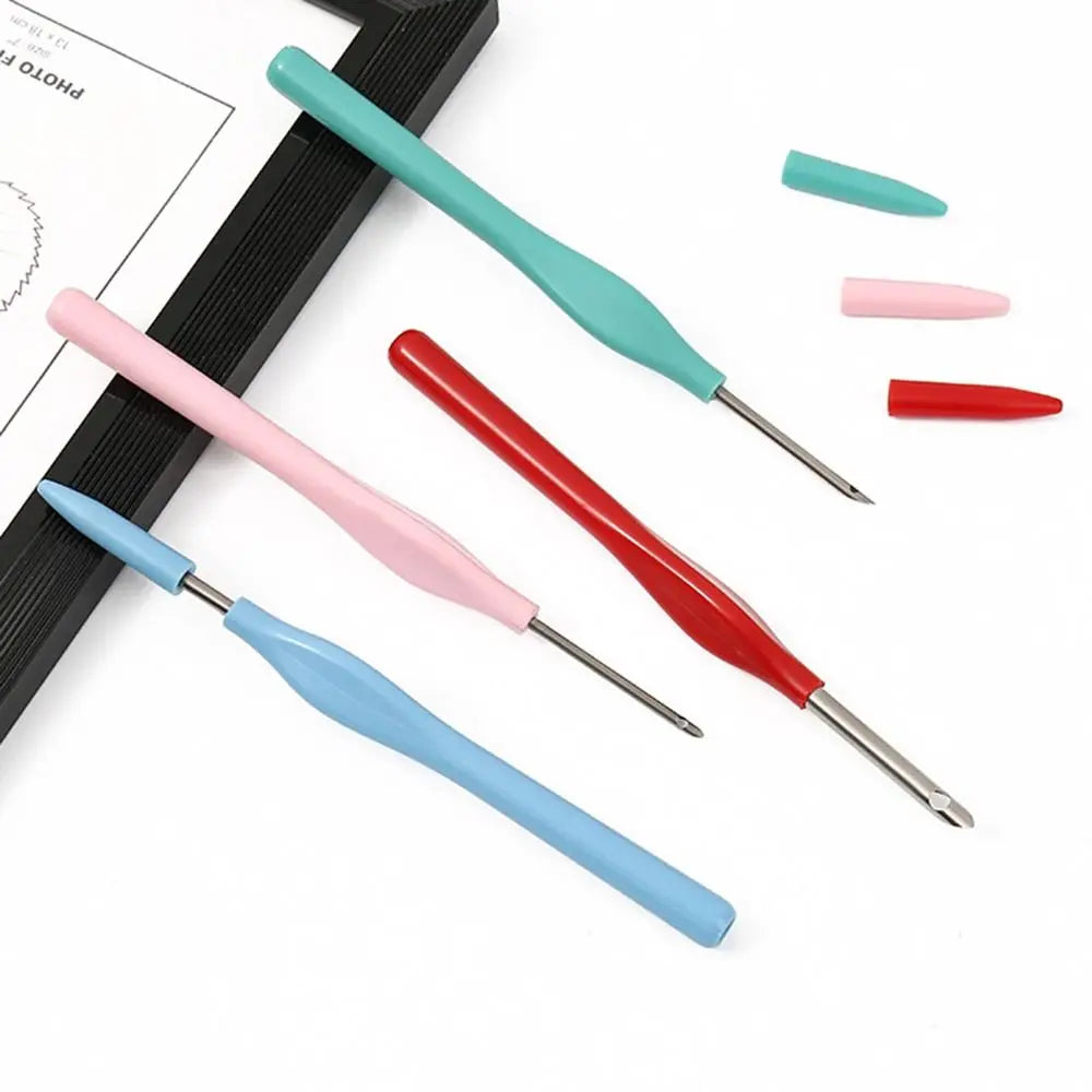 Stylos de broderie punch needle étalés sur une table avec leurs capuchons de couleur