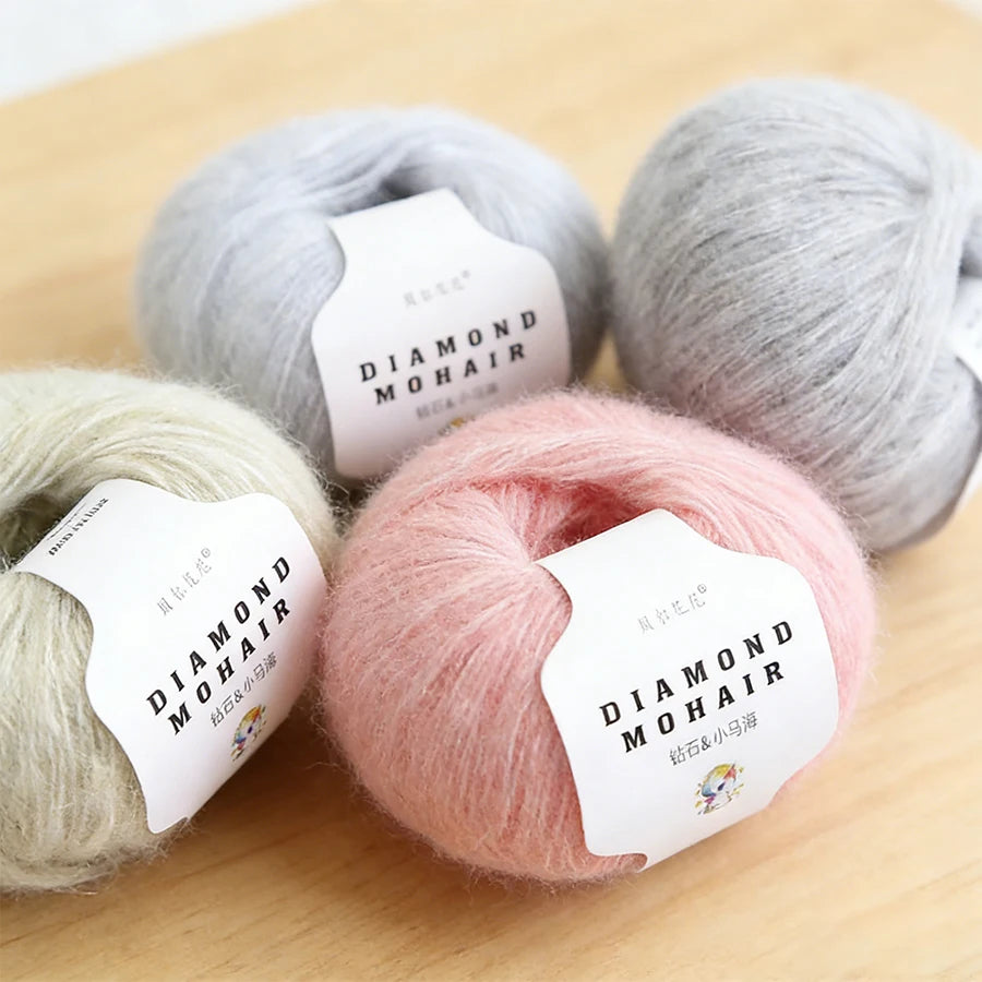 Assortiment de cinq pelotes de laine mohair douces posées sur une table en bois claire