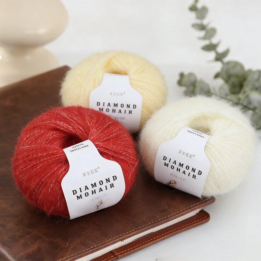 Trois pelotes de laine mohair rouge blanc et jaune à côté d'une branche d'eucalyptus