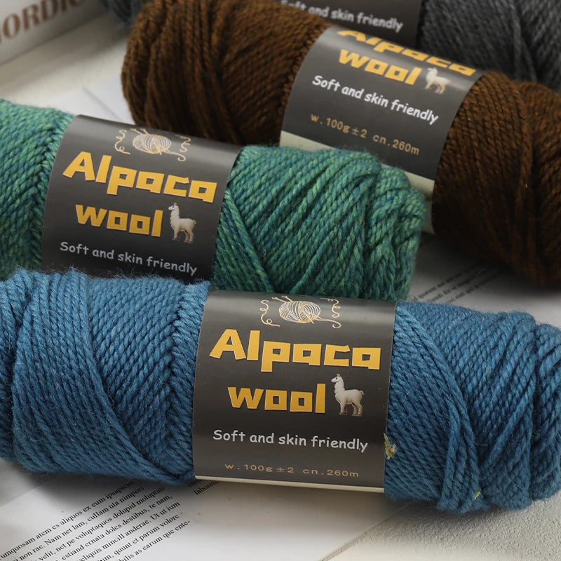 Gros plan sur trois pelotes de laine Alpaca Wool de couleurs bleu canard vert forêt et marron