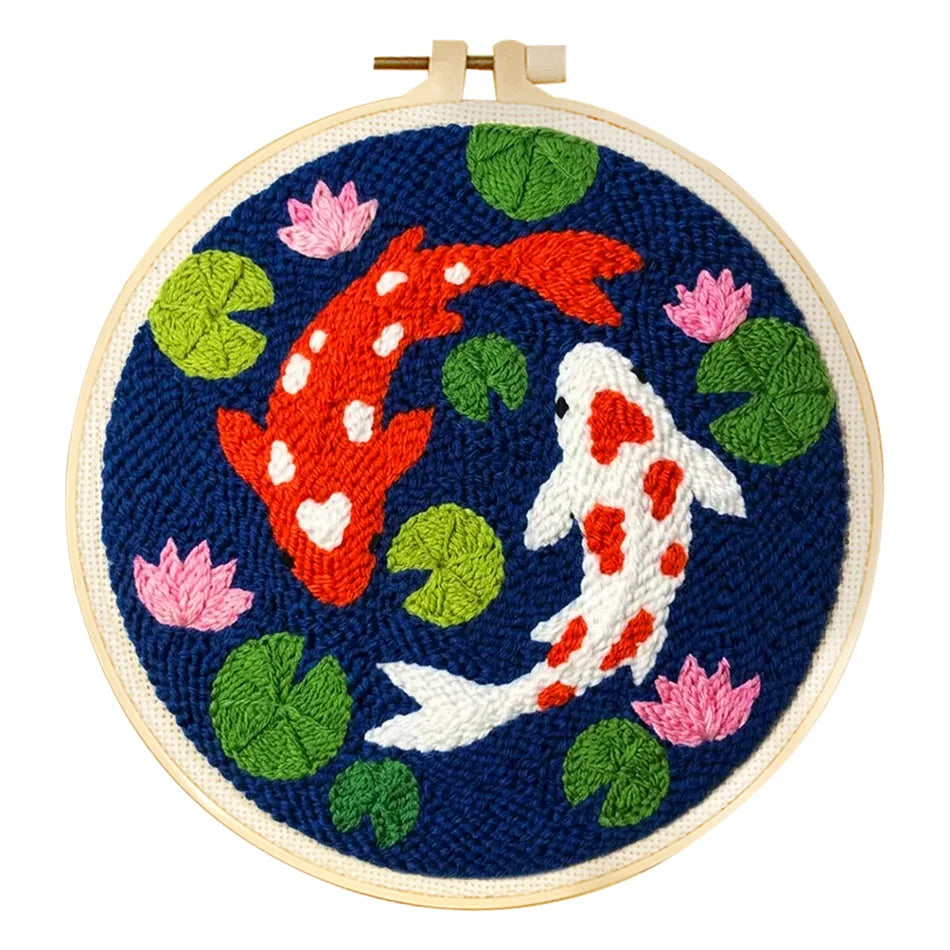 Kit punch needle fini représentant deux carpes koi japonaises rouge et blanche nageant au milieu de nénuphars sur toile tendue bleu marine.