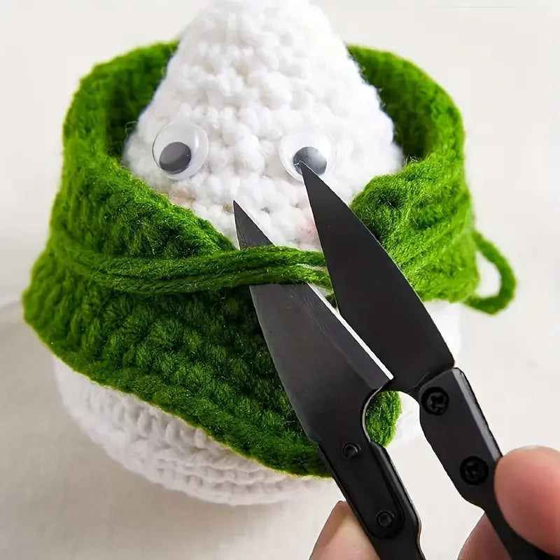 Main utilisant un mini ciseau coupe-fil noir pour couper les fils d'une peluche faite main