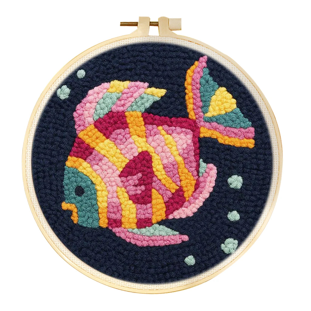 Cercle à broder punch needle avec un gros poisson tropical multicolore aux couleurs de l'arc-en-ciel sur un tissu bleu foncé.